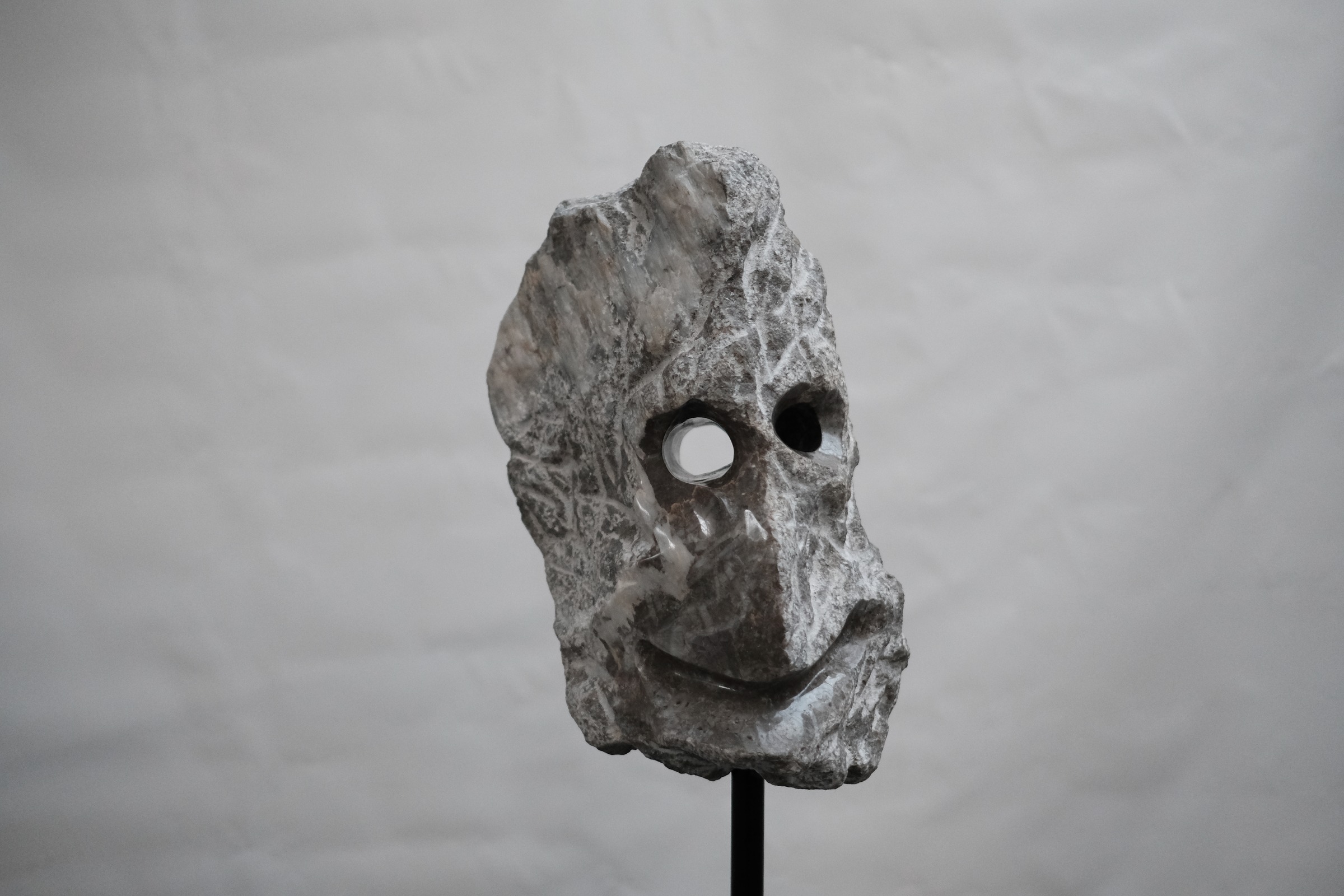 SIVI, an angular limestone face with circular apertures, displayed on a black mount